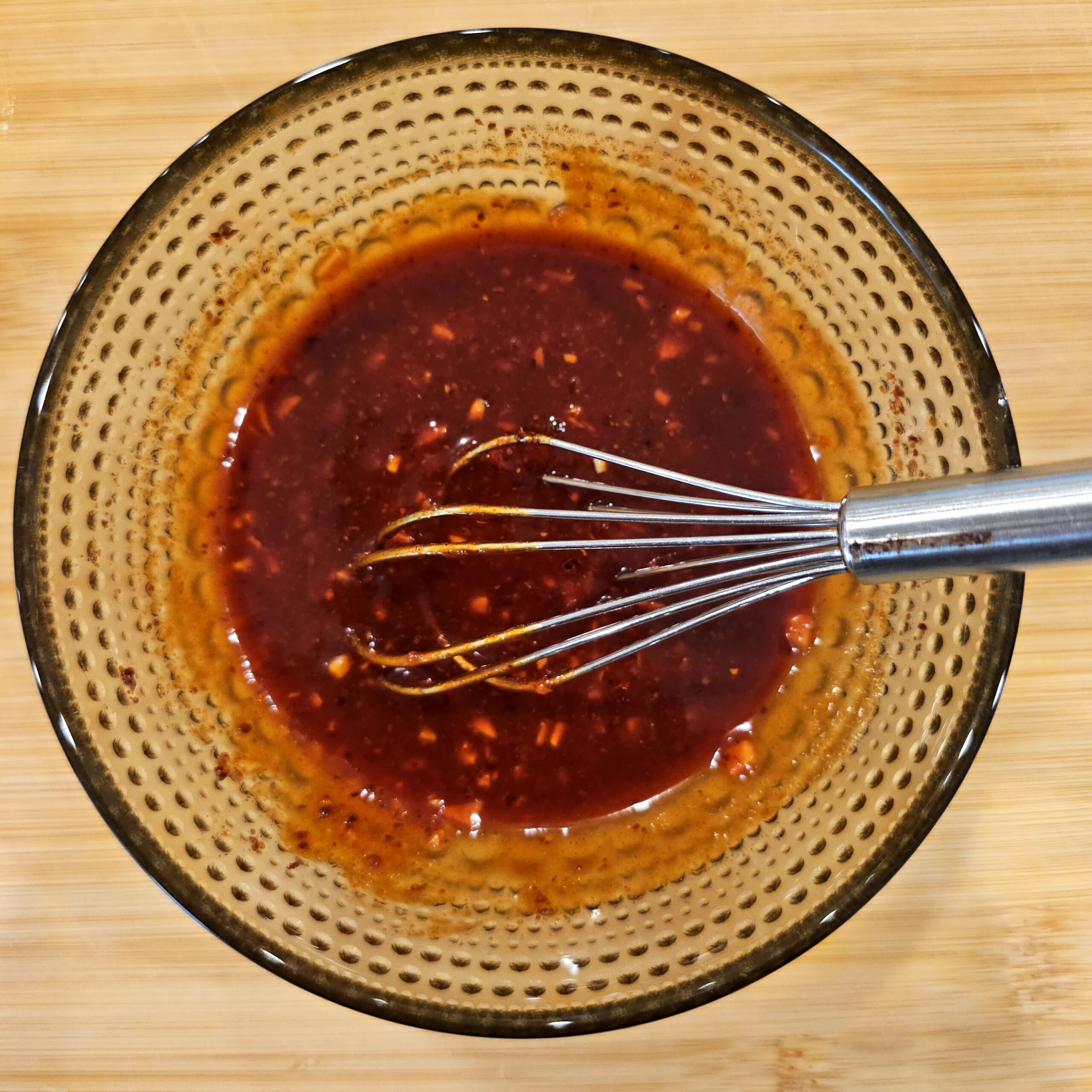 Red tteokbokki sauce being whisked in a ceramic bowl.