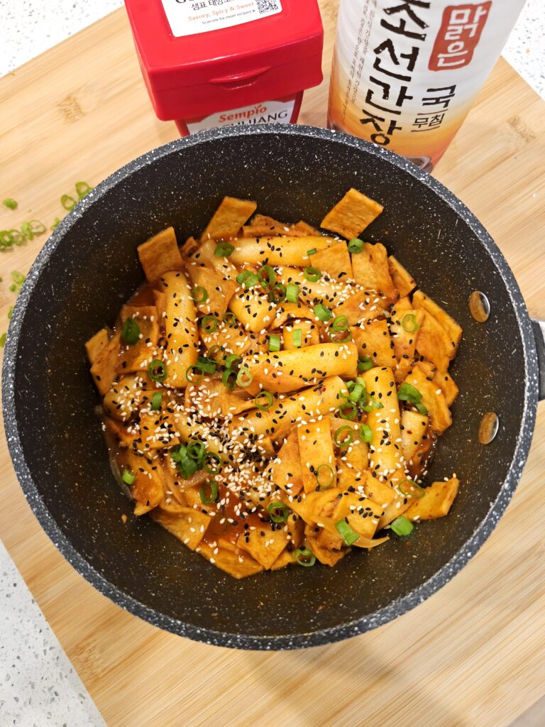 Spicy tteokbokki topped with sesame seeds and green onions ready to be served.