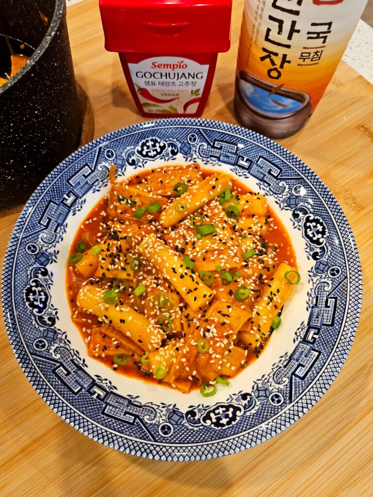 A blue and white patterned plate filled with spicy Korean rice cakes and fish cakes.