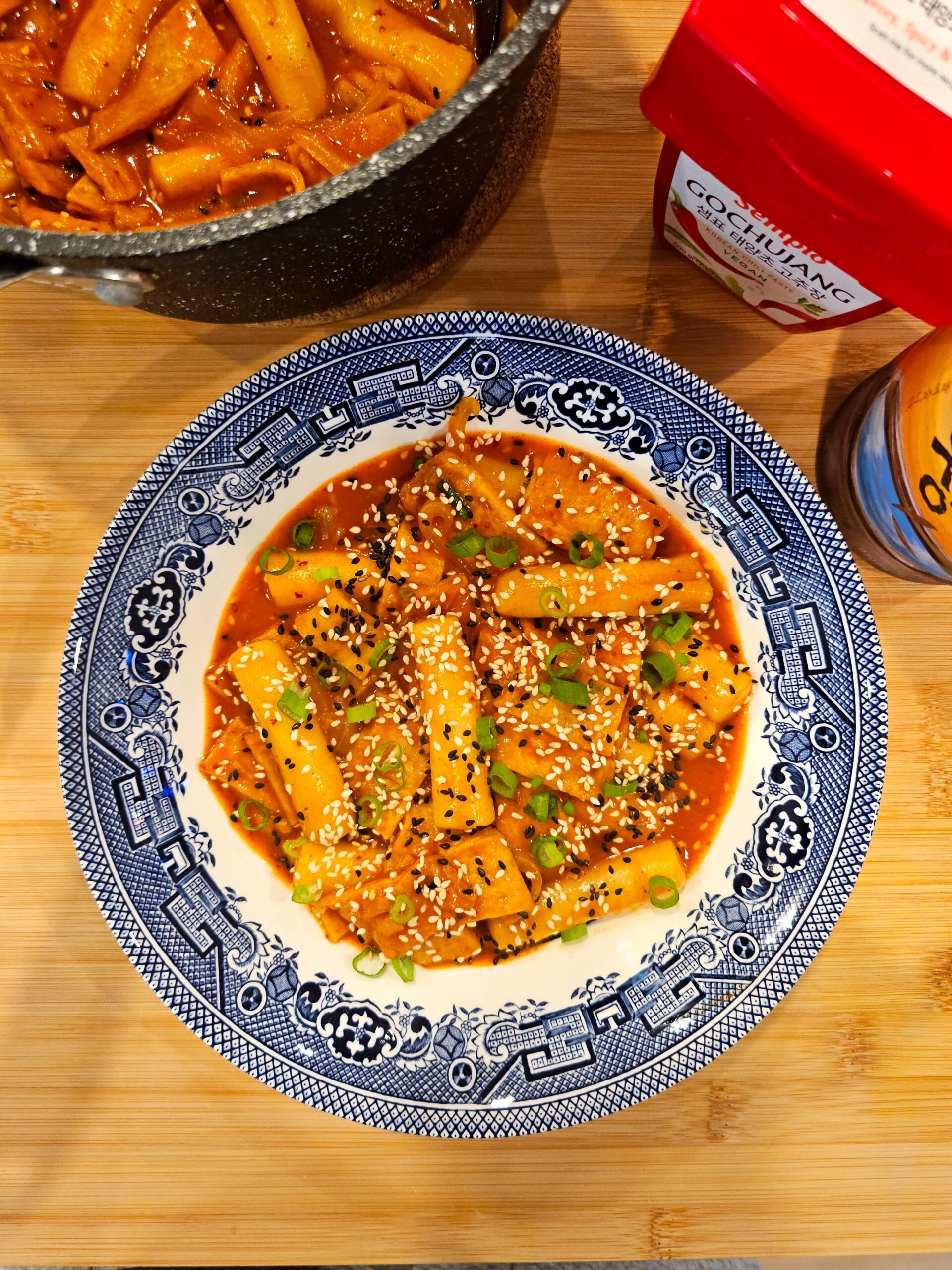 A blue and white patterned plate filled with spicy Korean rice cakes and fish cakes.