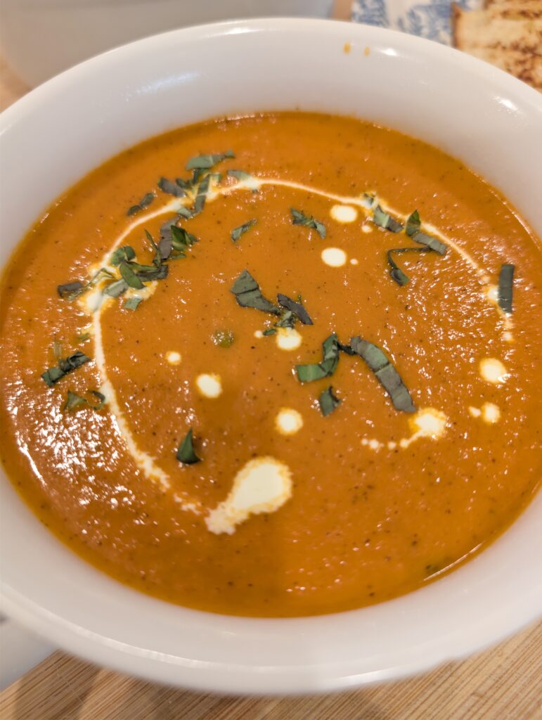 Close up shot of the herb and cream garnish on top of a bowl of tomato soup.