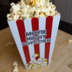 Movie night popcorn box filled with sweet and salty ghee popcorn on a wooden surface with a blurred background