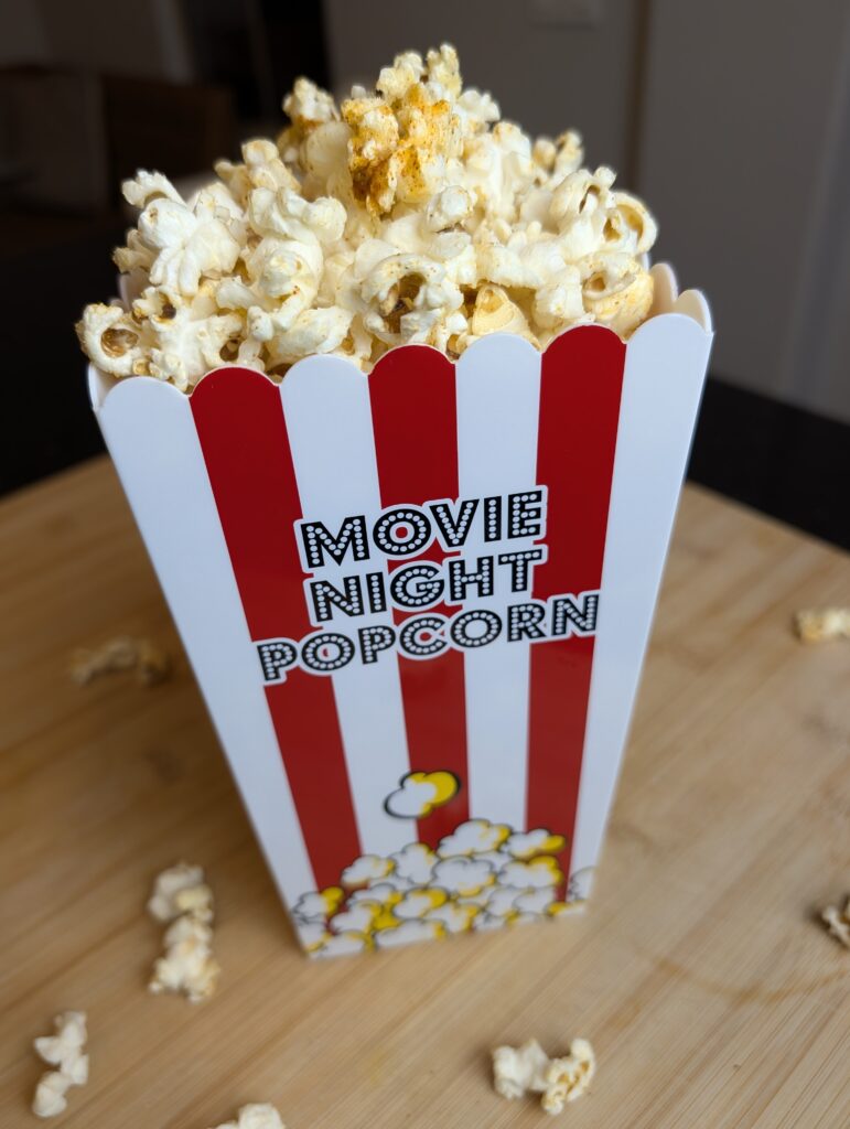 Movie night popcorn box filled with sweet and salty ghee popcorn on a wooden surface with a blurred background