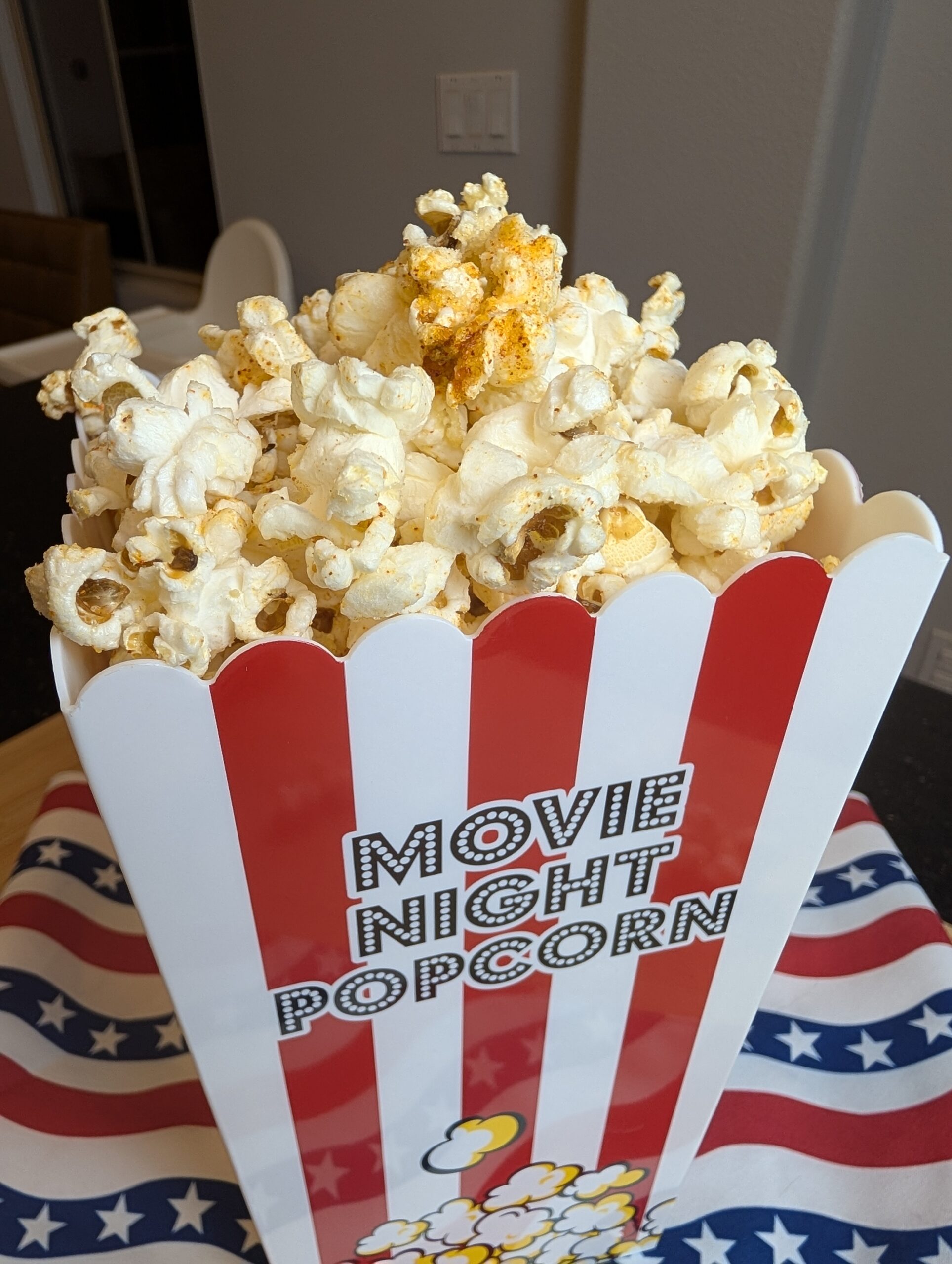 Movie night popcorn box filled with sweet and salty ghee popcorn on a wooden surface with a blurred background